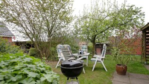 Ein Garten mit Grill, Sitzgelegenheit und einem Blumentopf.