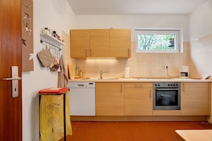 A modern kitchen with wooden cabinets, a dishwasher, an oven, and a window providing natural light.