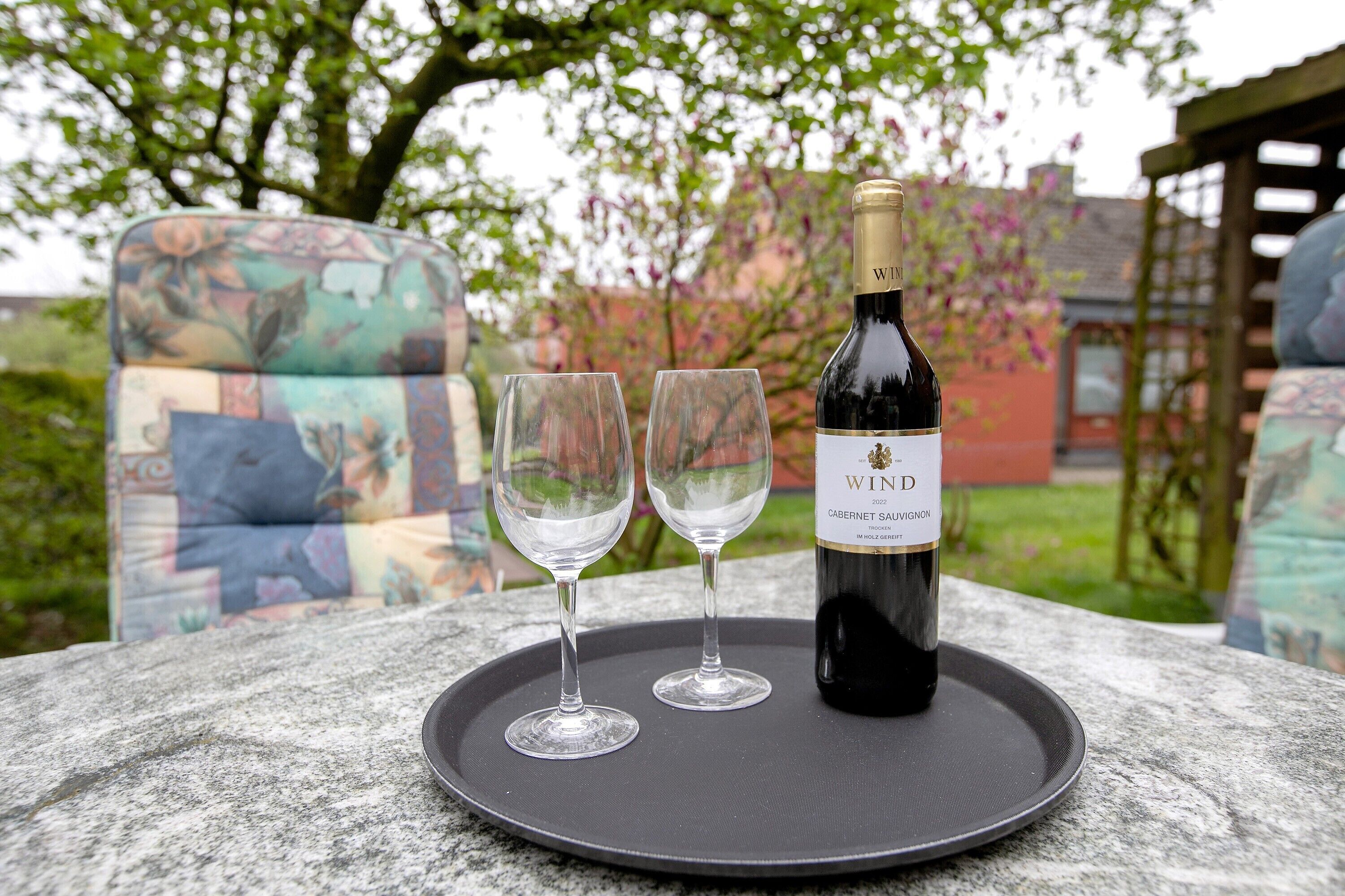 A bottle of wine and two glasses on a tray.