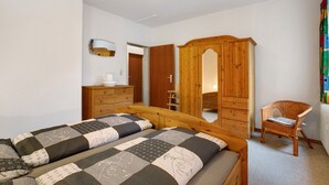 Ein Schlafzimmer mit zwei Betten, einem Holzschrank, einem Stuhl und einem Spiegel.