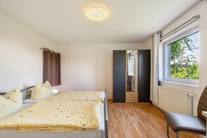 A bedroom with a bed, a chair, a window with a view, and a door leading to another room.