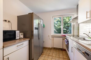 A kitchen with a refrigerator, microwave, toaster, and sink.