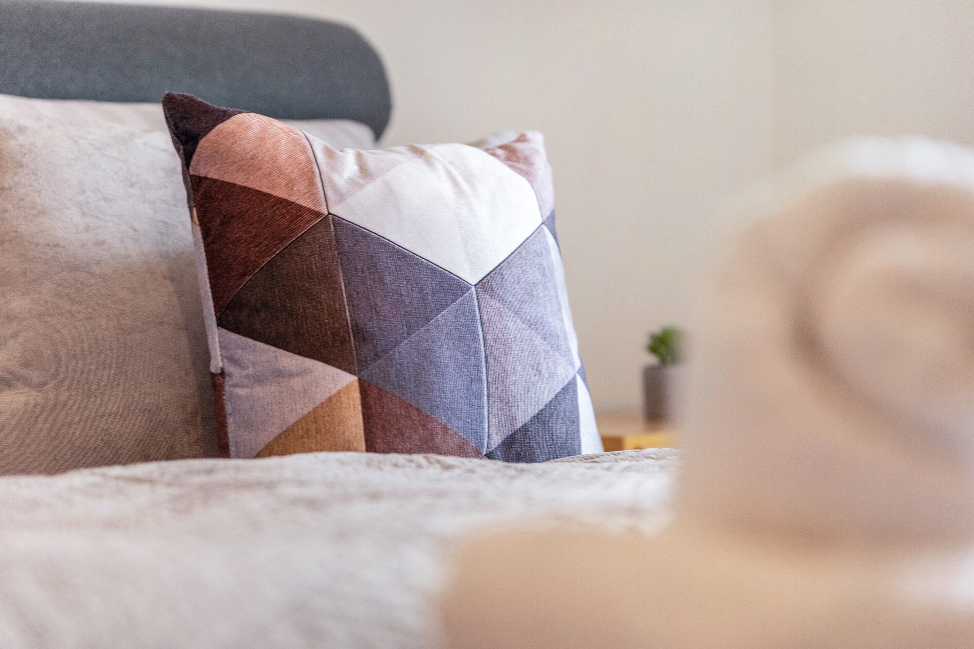 Ein Bett mit einem Kopfkissen mit geometrischem Muster und einem schlichten Kopfkissen.