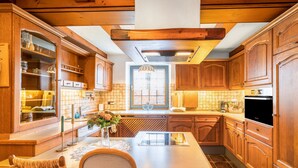 Una cocina con armarios de madera, una isla central, una mesa de comedor y una ventana con vistas.