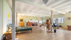 Amplia habitación con cama, suelo de madera, una mesa de comedor, sillas y una zona de cocina.