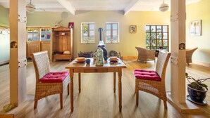 Un comedor con una mesa de madera, sillas de mimbre y una planta en maceta.