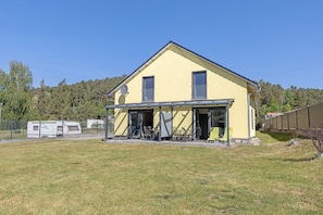 Une maison jaune à deux étages, dotée d’un patio couvert, d’une antenne parabolique et d’une cour clôturée.