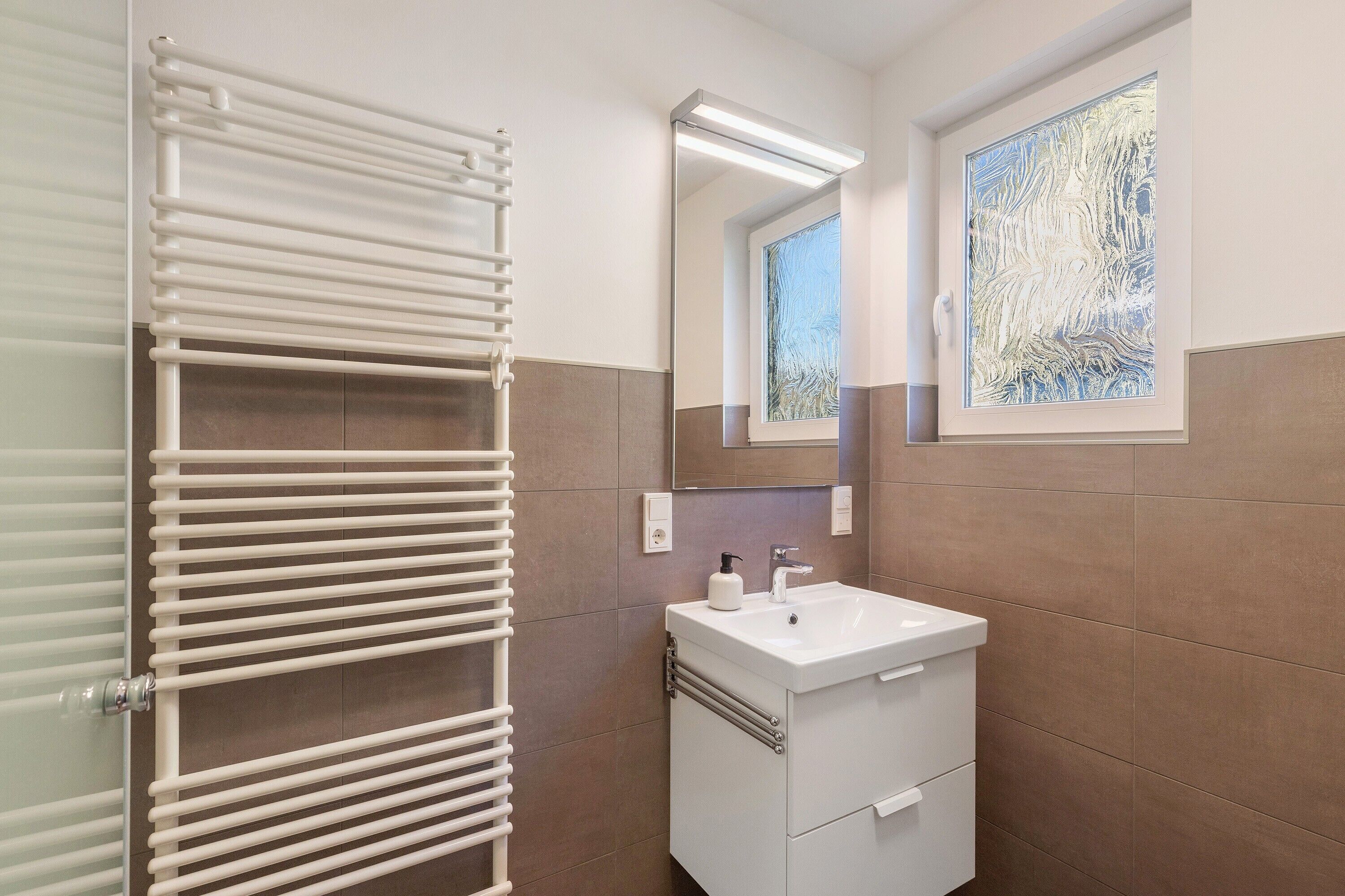 A bathroom with a white sink, mirror, and towel rack.