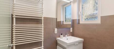 A bathroom with a white sink, mirror, and towel rack.