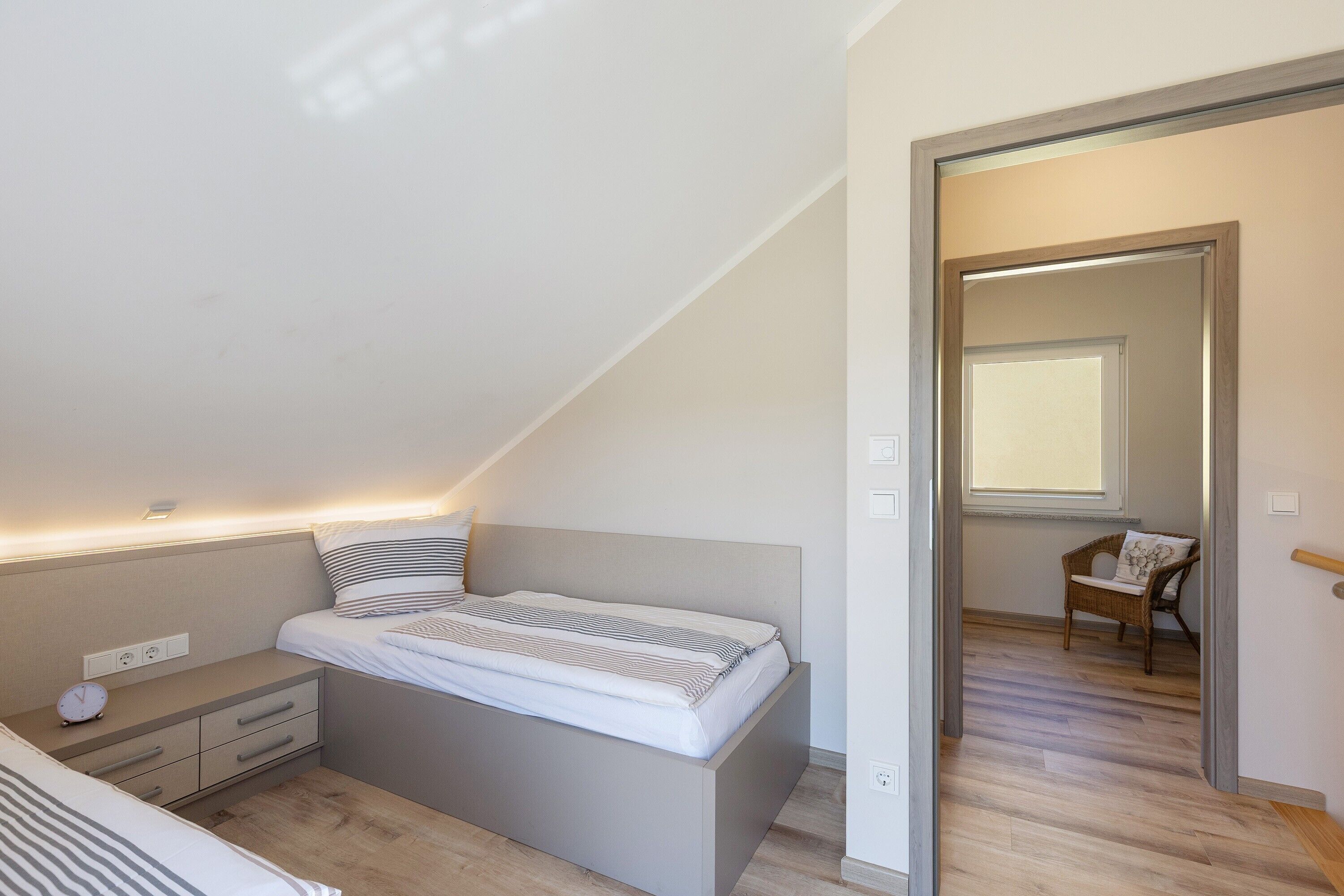 A bedroom with a bed, bedside table, and a chair in the corner.