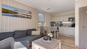 A modern living room with a grey sofa, a coffee table with a vase, and a dining area with chairs and a table.
