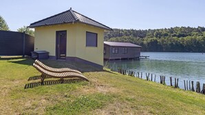 Järven rannalla sijaitseva rakennus, jossa on penkki, ovi ja ikkuna.