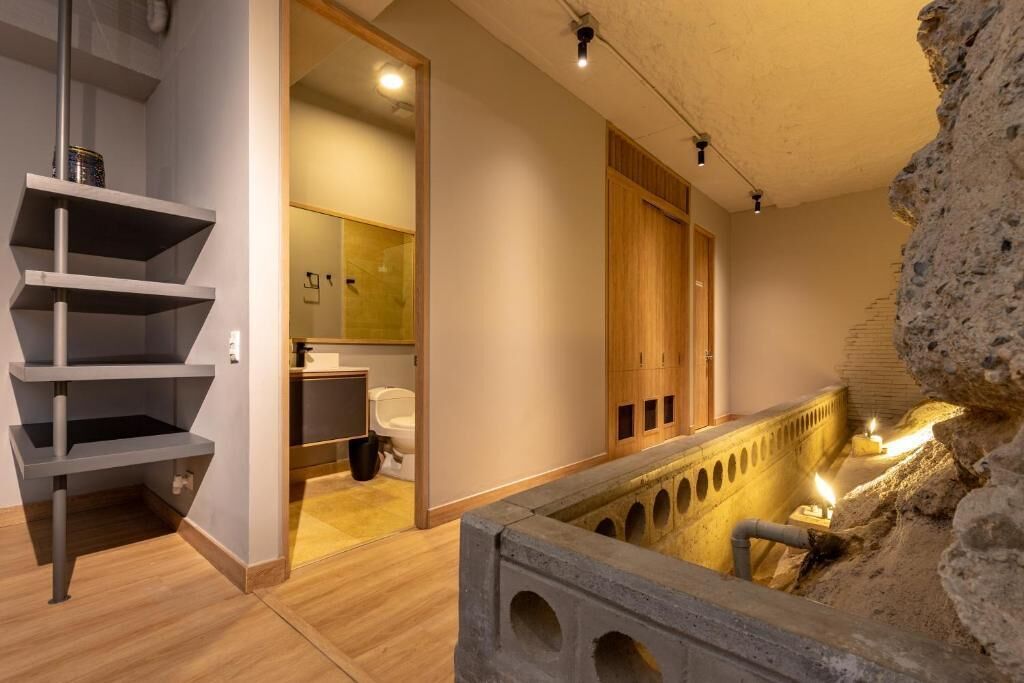 A modern interior with a staircase, wooden cabinets, and a unique stone feature.