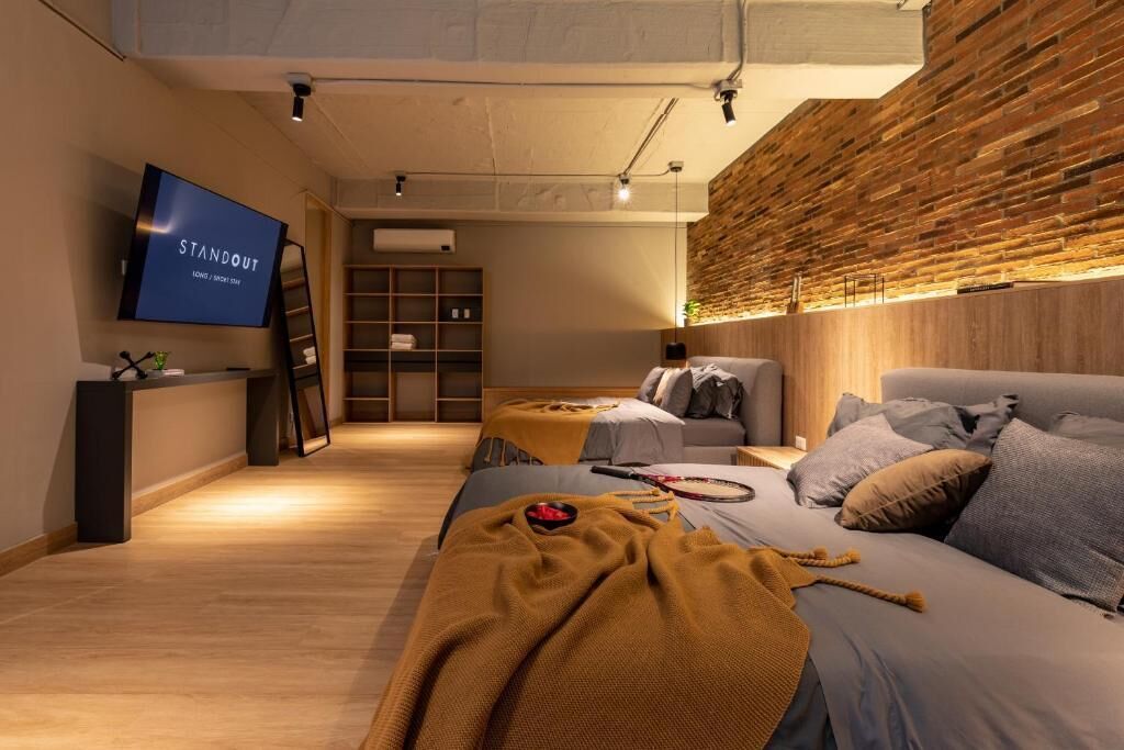Una habitación de hotel moderna con una cama grande, un televisor, una pared de madera y una estantería.