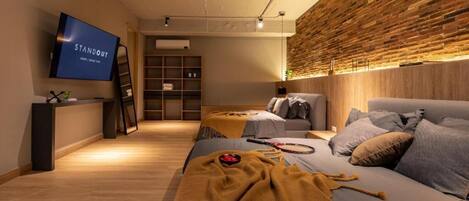 Una habitación de hotel moderna con una cama grande, un televisor, una pared de madera y una estantería.