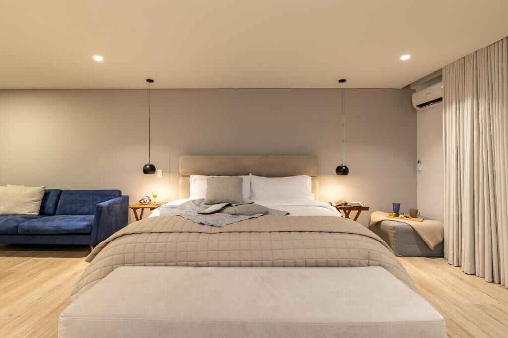Un dormitorio moderno con una cama grande, un sofá azul y una mesita de noche con una lámpara.