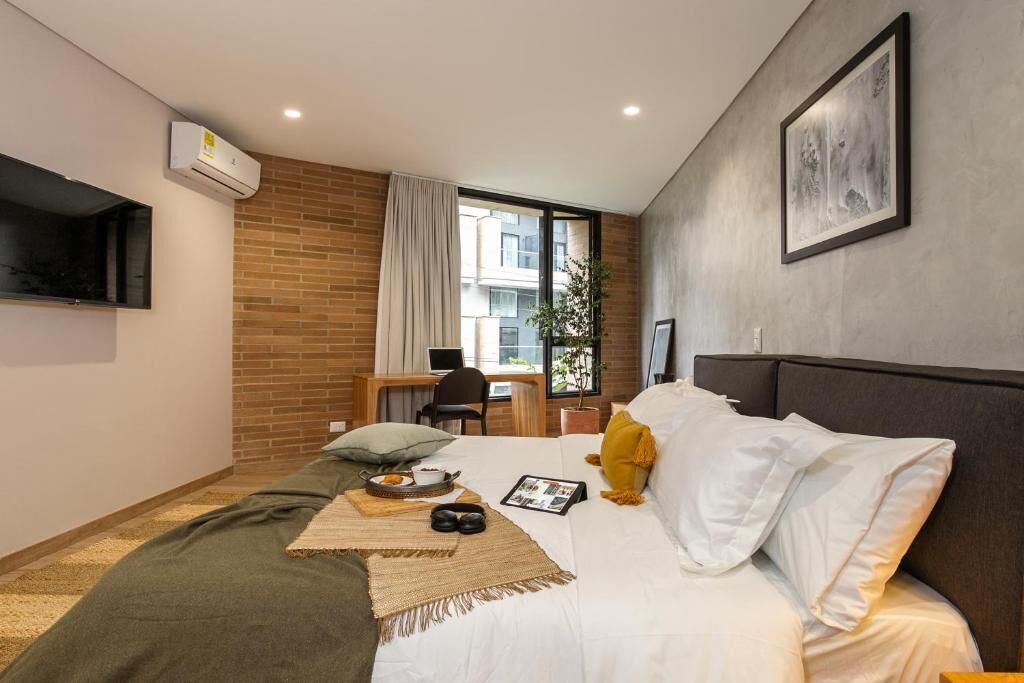Et moderne hotelværelse med en stor seng, et skrivebord og et fjernsyn ophængt på væggen.