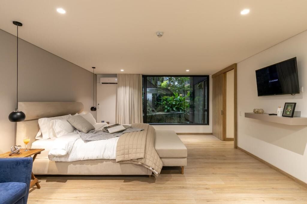 Une chambre à coucher moderne avec un lit, une table de chevet et un téléviseur fixé au mur.