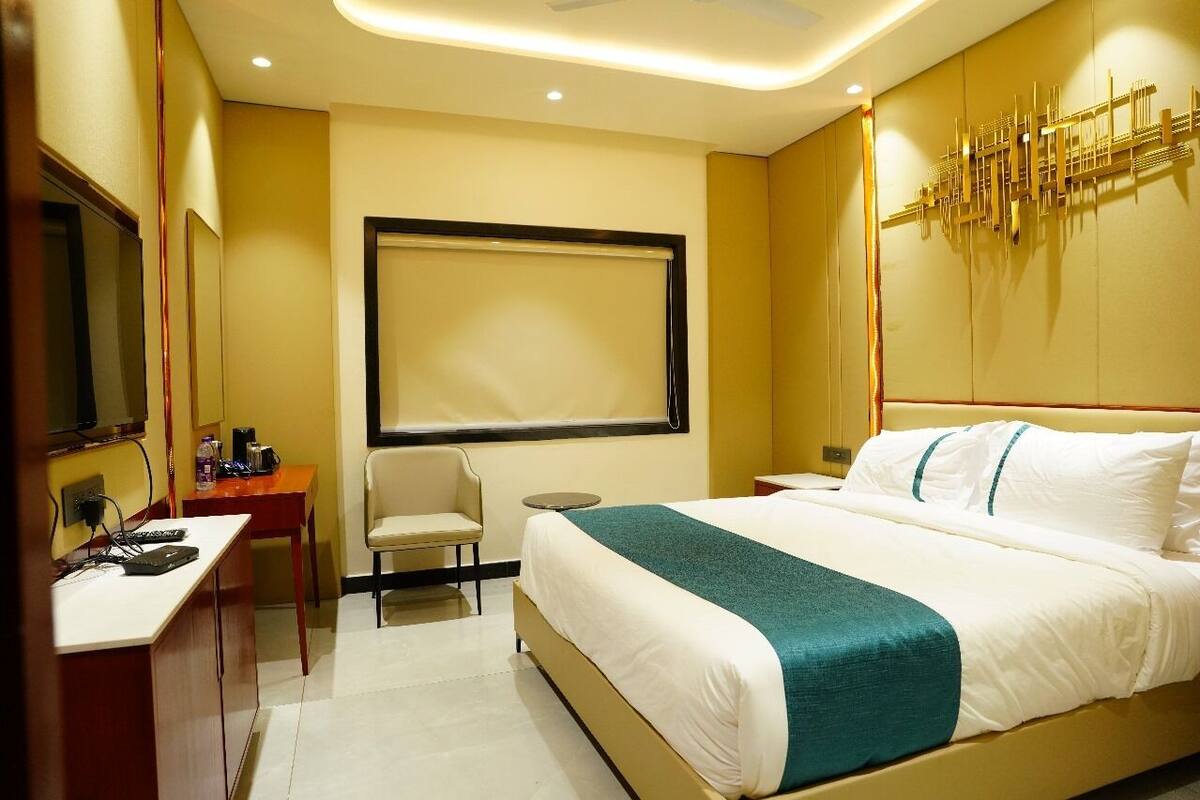 Une chambre d’hôtel équipée d’un lit, d’un bureau, d’une chaise, d’une télévision et d’une œuvre d’art accrochée au mur.