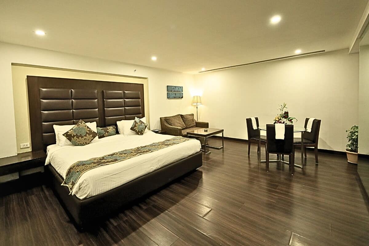 A modern hotel room with a large bed, a desk, and a chair.