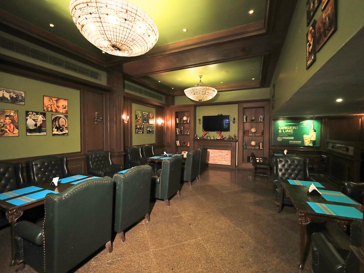 A restaurant with booths and tables, a bar area, and a television screen displaying an advertisement.