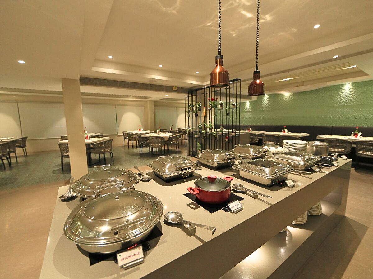 Un buffet avec différents récipients et ustensiles pour servir les aliments, un pot rouge et des lampes suspendues décoratives.