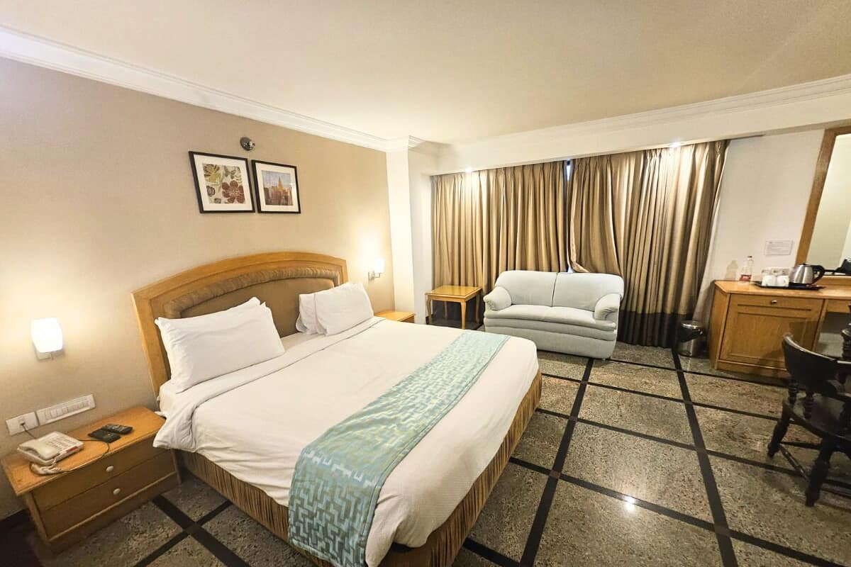 A hotel room with a large bed, a desk, a chair, and a small table.