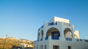 A white building with blue balconies and arches, set against a clear sky. - Villa Eva with Panoramic view (Santorini)