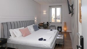 A modern bedroom with a large bed, bedside tables, a desk, and a chair. - Plaza Suites Rome (Rome)