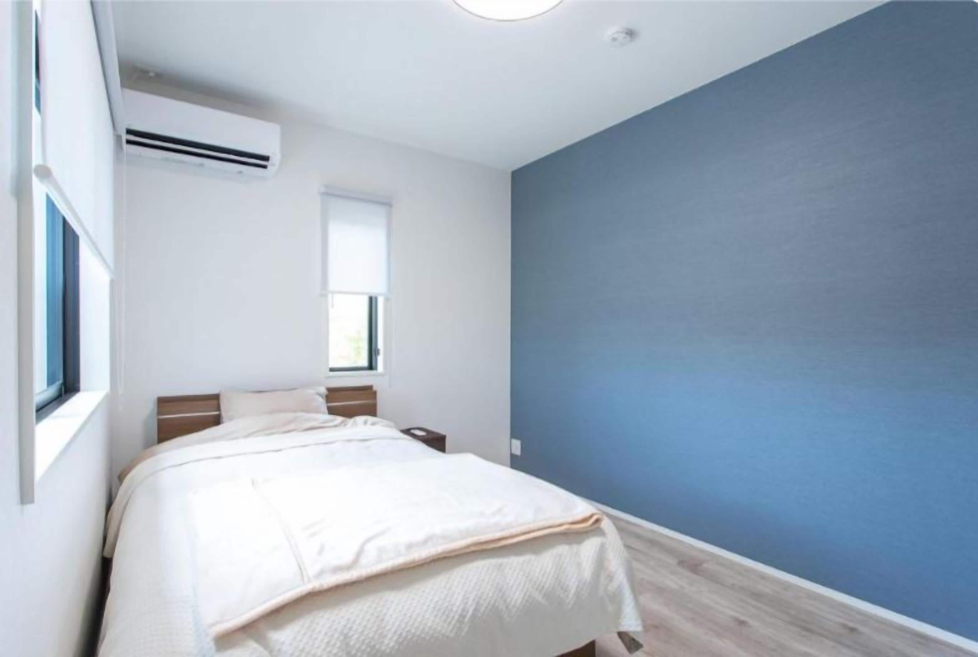 A bedroom with a bed, a window, and a wall-mounted air conditioner.