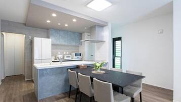 Una cocina moderna con comedor, armarios blancos y encimera gris.