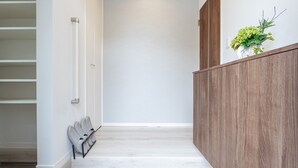 A hallway with a wooden wall, a white door, and a shoe rack. - Mova Villa Okino (Kikuyo)