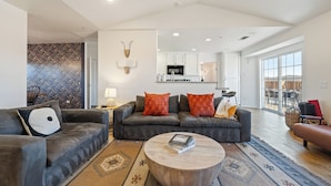 A modern living room with a grey sofa set, a round wooden coffee table, and a patterned rug.