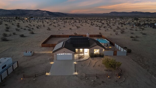 A modern house with a large garage, a swimming pool, and a well-maintained yard in a desert landscape.