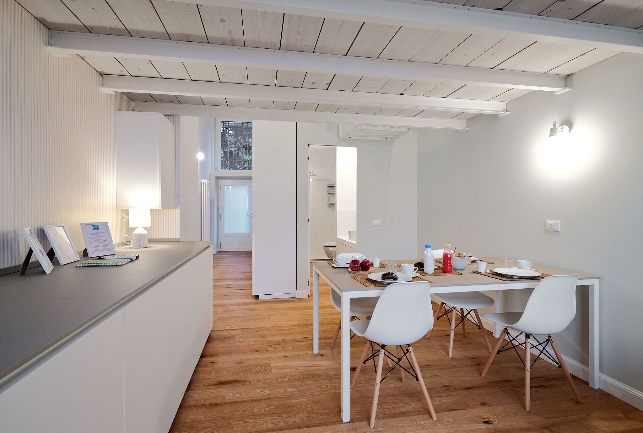 A modern kitchen with white cabinetry, a wooden countertop, and a dining area with a white table and chairs.