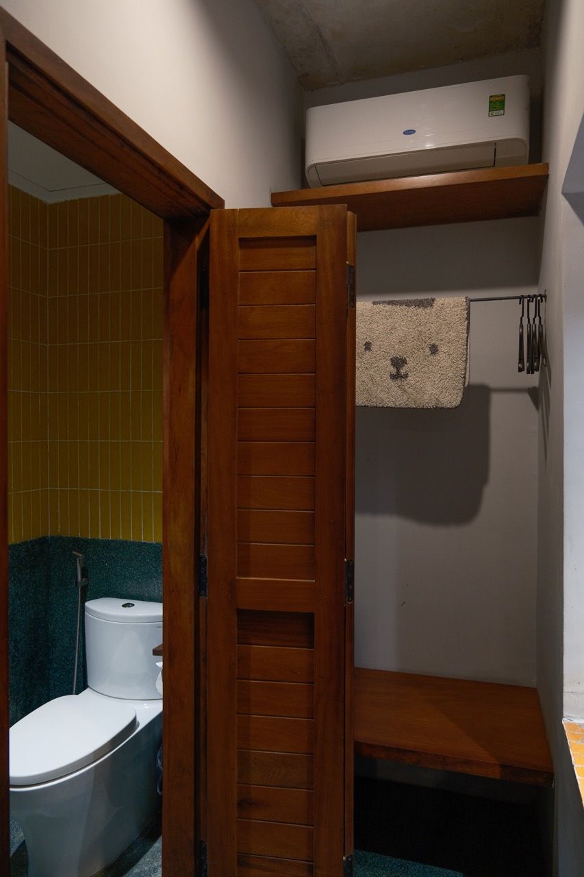 A bathroom with a toilet, a towel rack, and a wooden door.
