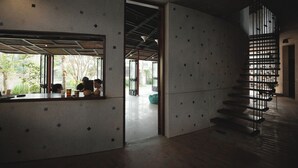 A modern interior with a bar area, a staircase, and a view through a glass door. - De Hué Space (Hue)