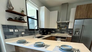 A modern kitchen with a central island, bar stools, and a built-in refrigerator.