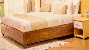 Un lit bien fait, avec une tête de lit en bois, une table de chevet dotée d’un tiroir et un tableau accroché au mur.
