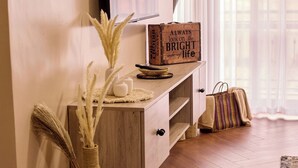 Un plancher en bois, un téléviseur fixé au mur, un vase décoratif, une valise et un panneau avec l’inscription : « Il faut toujours voir le bon côté des choses. »