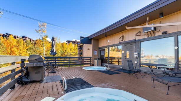 A deck with hot tubs, outdoor seating, and a grill area. - Hike In/Hike Out w/Slope Views + 3 Hot Tubs-Ski/Town Shuttle-Sauna-Gym-Gas Fireplace-Deck-Updated (Steamboat Springs)