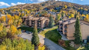 A multi-story hotel with a parking lot, surrounded by autumn-colored trees and a hilly backdrop. - Hike In/Hike Out w/Slope Views + 3 Hot Tubs-Ski/Town Shuttle-Sauna-Gym-Gas Fireplace-Deck-Updated (Steamboat Springs)