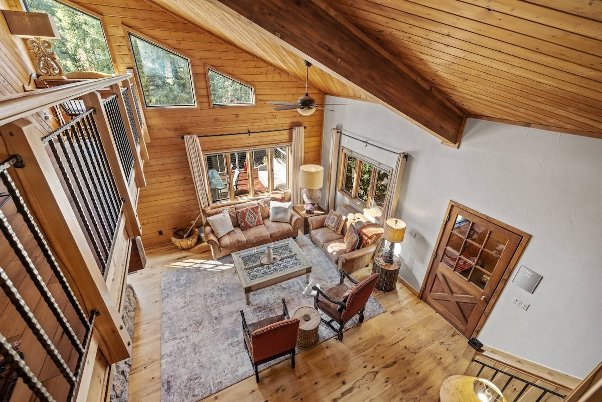 Un vaste espace de vie de style loft, doté d’un haut plafond, de poutres en bois et de grandes fenêtres offrant une vue sur l’extérieur.