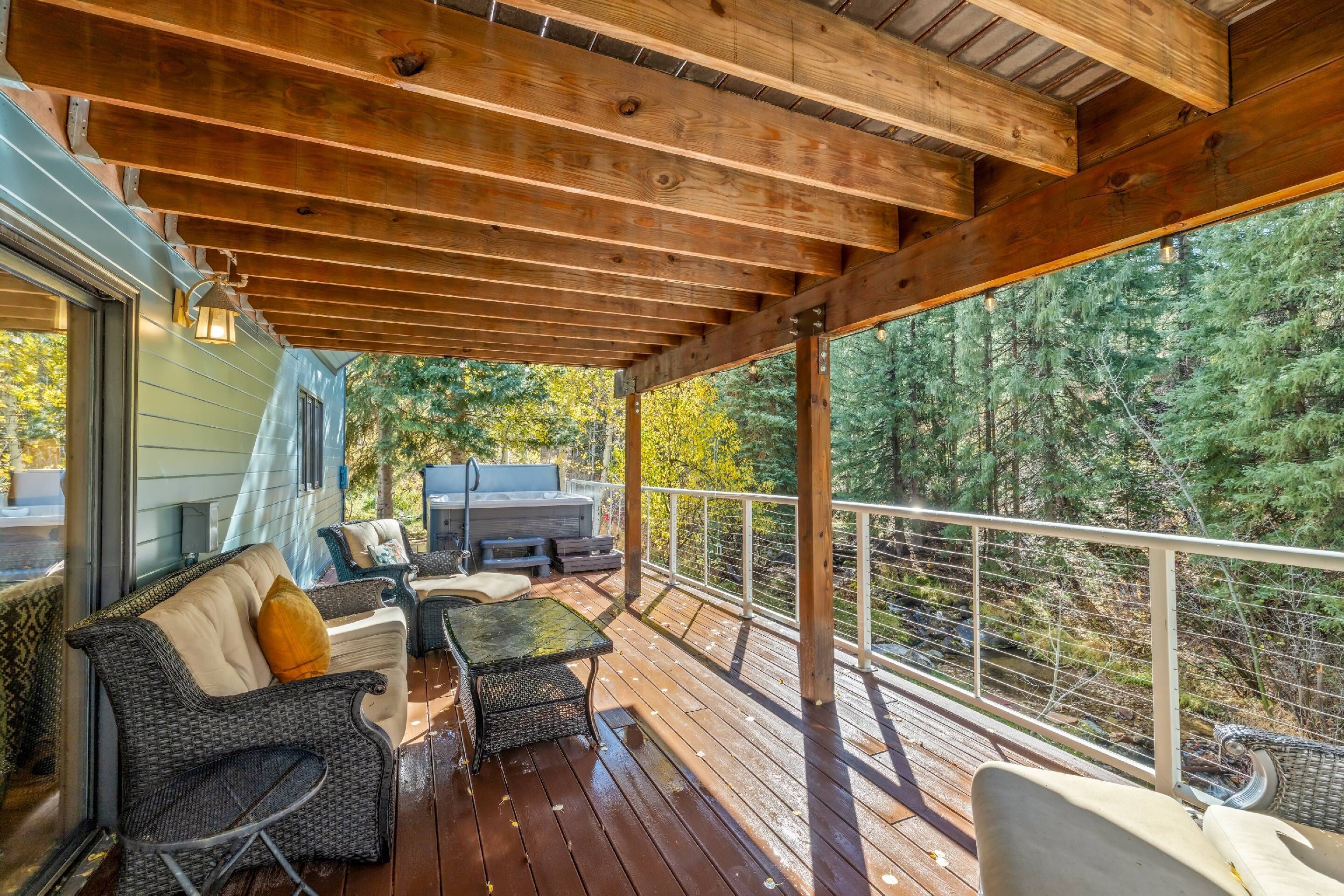 Un terrazzo in legno con mobili da esterno, un barbecue e vista sugli alberi.