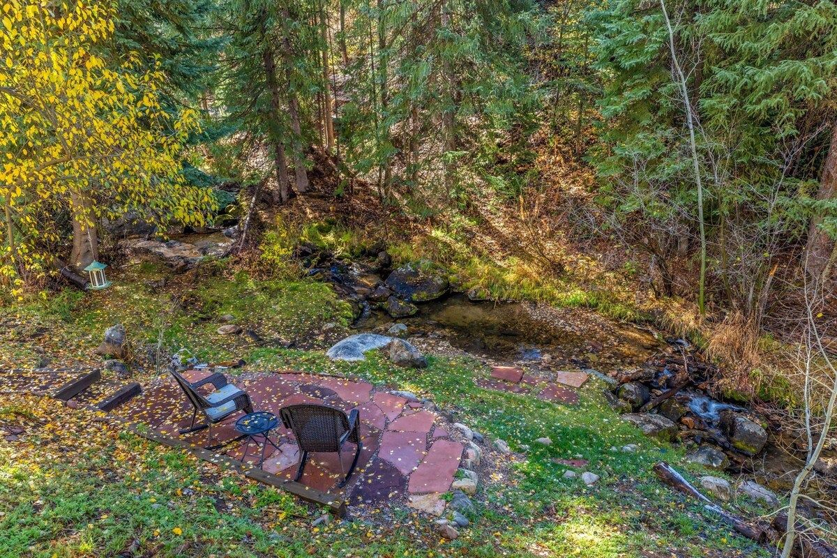 A rustic outdoor seating area with stone steps, a fire pit, and a small table.