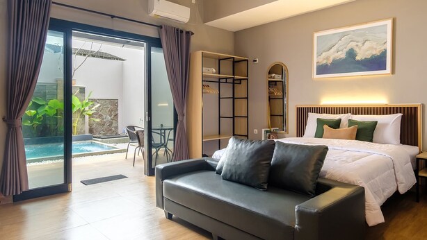 Habitación de hotel moderna con cama, sofá, vista a la piscina y zona de comedor.
