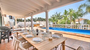 A covered outdoor dining area with a pool in the background. - Luxury villa with sauna and private pool in Denia 10P (Denia)
