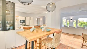 A modern kitchen with a wooden table, wicker chairs, and a glass cabinet with dishes. - Luxury villa with sauna and private pool in Denia 10P (Denia)