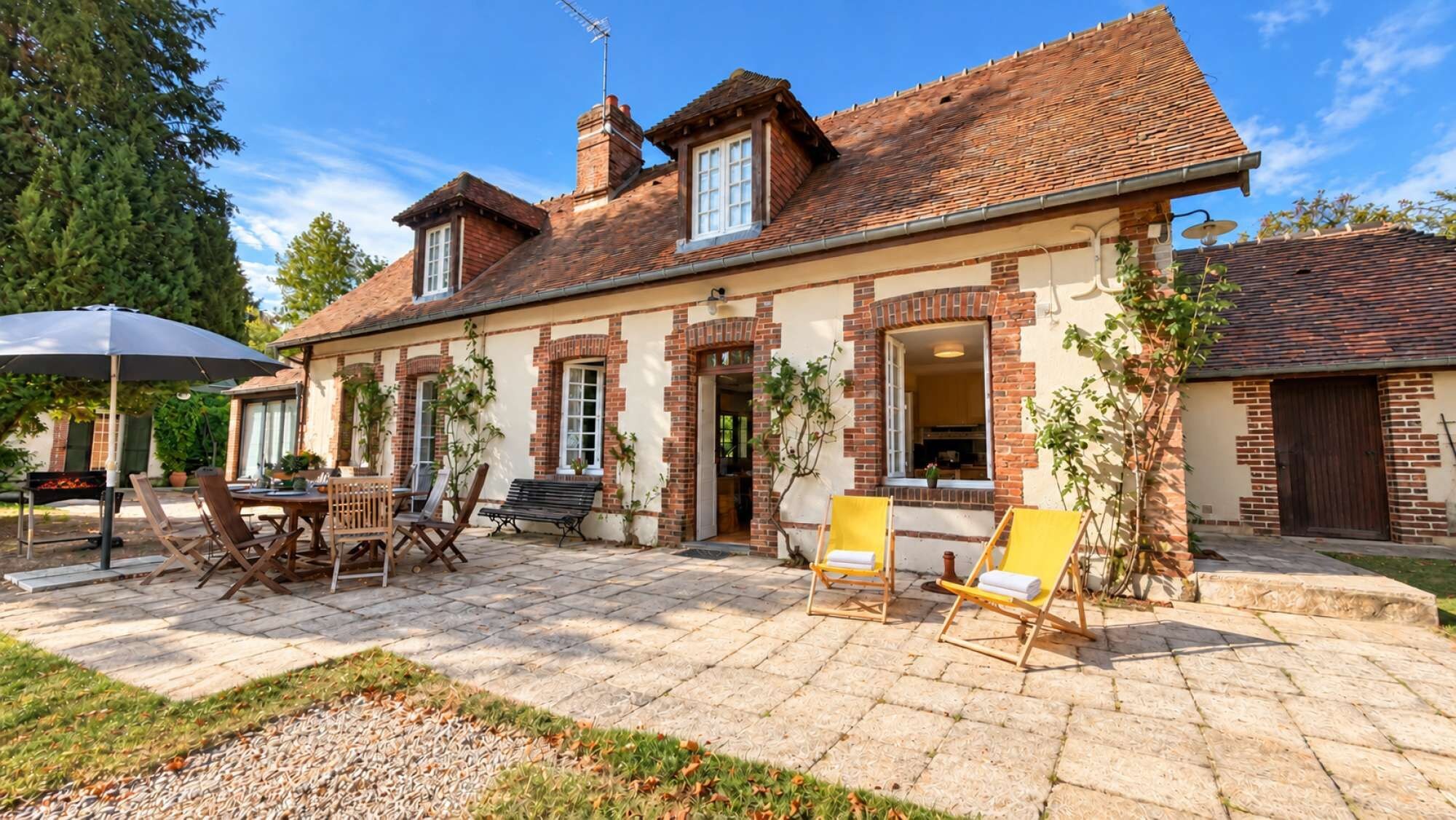 Ein zweistöckiges Haus mit Backsteinfassade, einer Terrasse und Gartenmöbeln sowie einer Sat-Anlage.