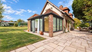 Une maison avec un patio, une véranda et un jardin.